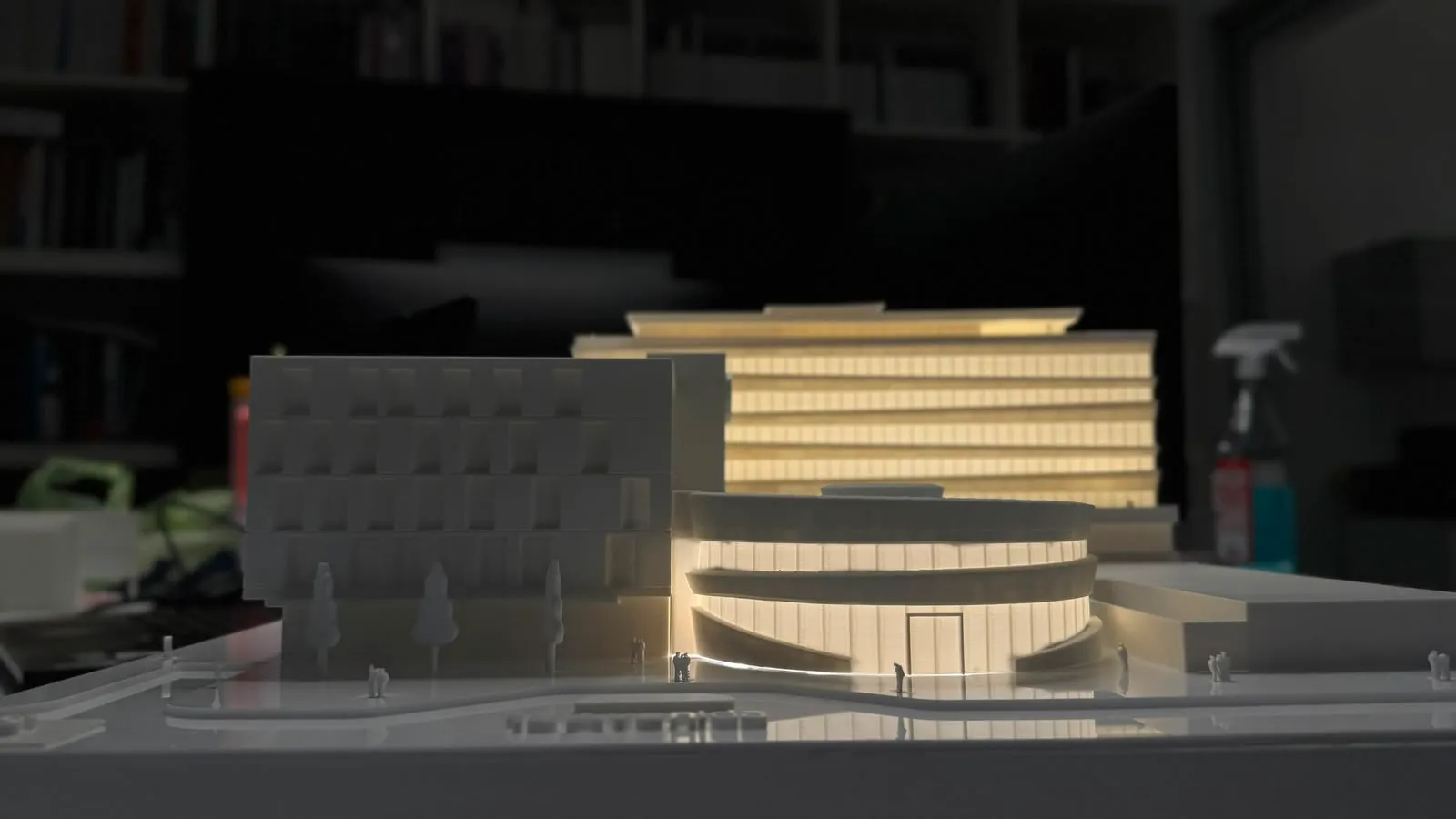 Maqueta de edificio con torre iluminada y figuras de escala