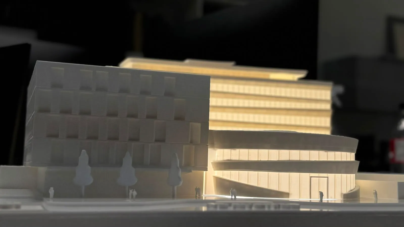 Maqueta arquitectónica con edificio curvo y torre iluminada