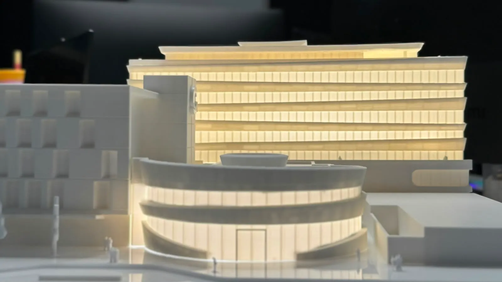 Maqueta arquitectónica en estudio con edificio curvo iluminado
