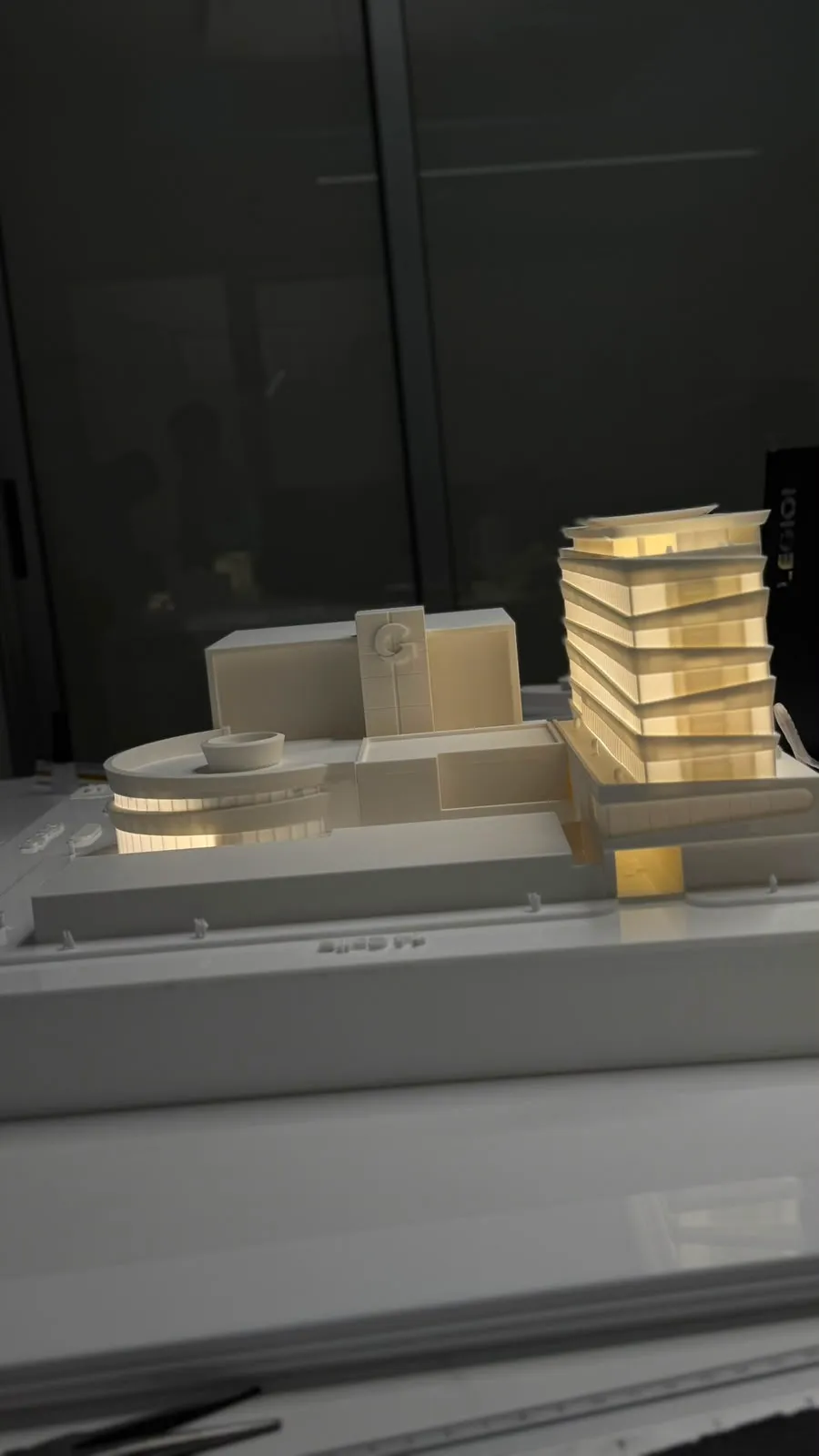 Maqueta arquitectónica vertical con torre escalonada e iluminación cálida
